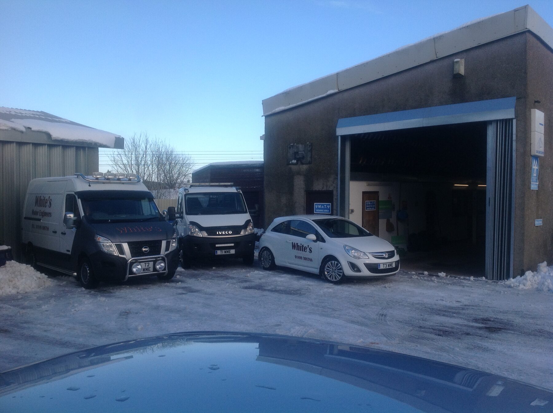 Workshop forecourt on a snowy morning with company vans