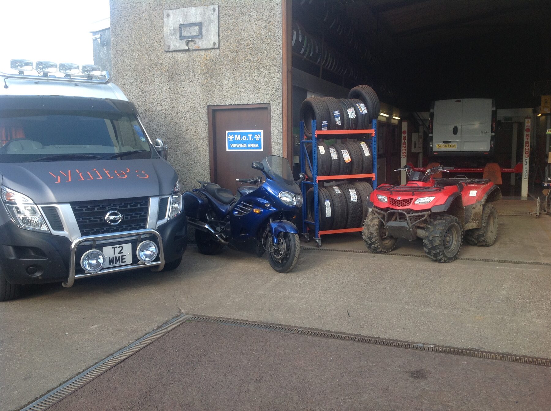 Company van, motorbike and quad bike outside the workshop with tyres racked behind